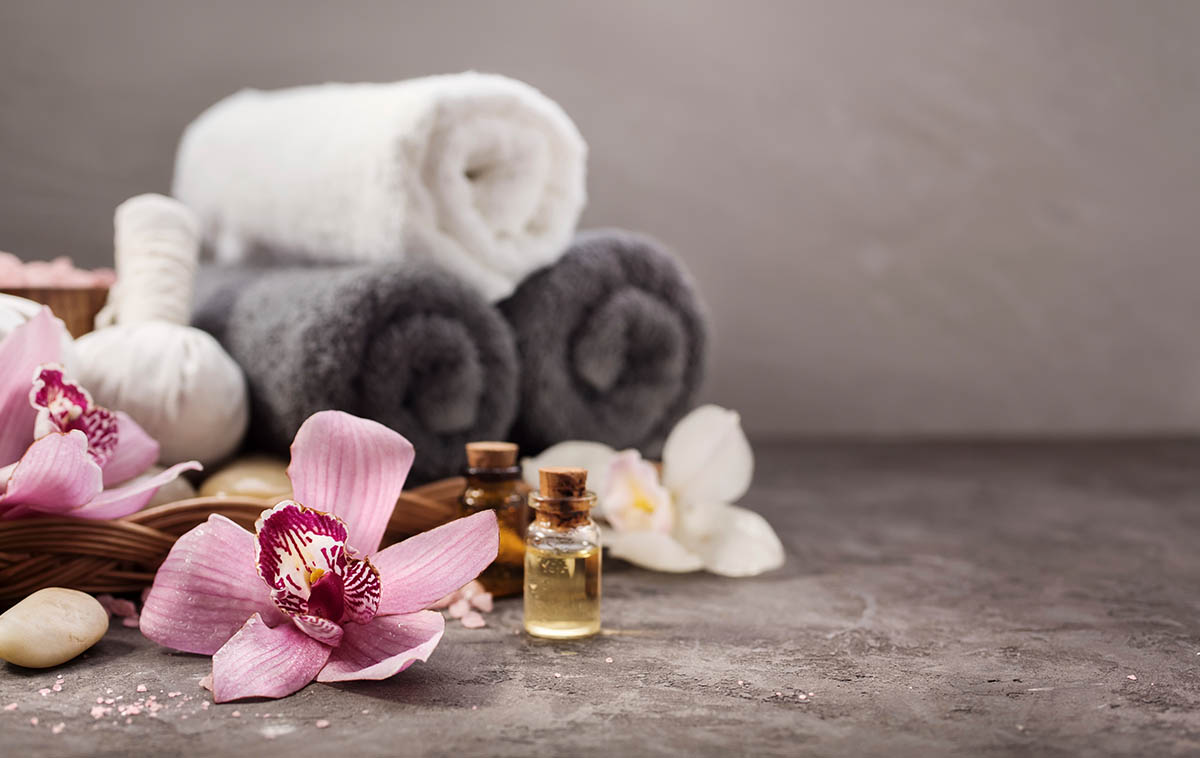 towels , flowers , essential oils and rocks on a table