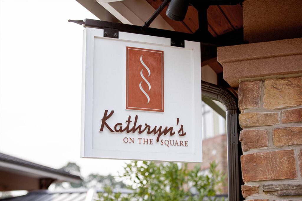 a sign for kathryn's on the square hangs from a brick wall