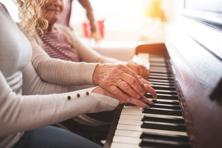 a woman is teaching another woman how to play the piano