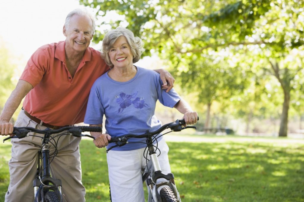 a man and woman are standing next to each other holding bicycles