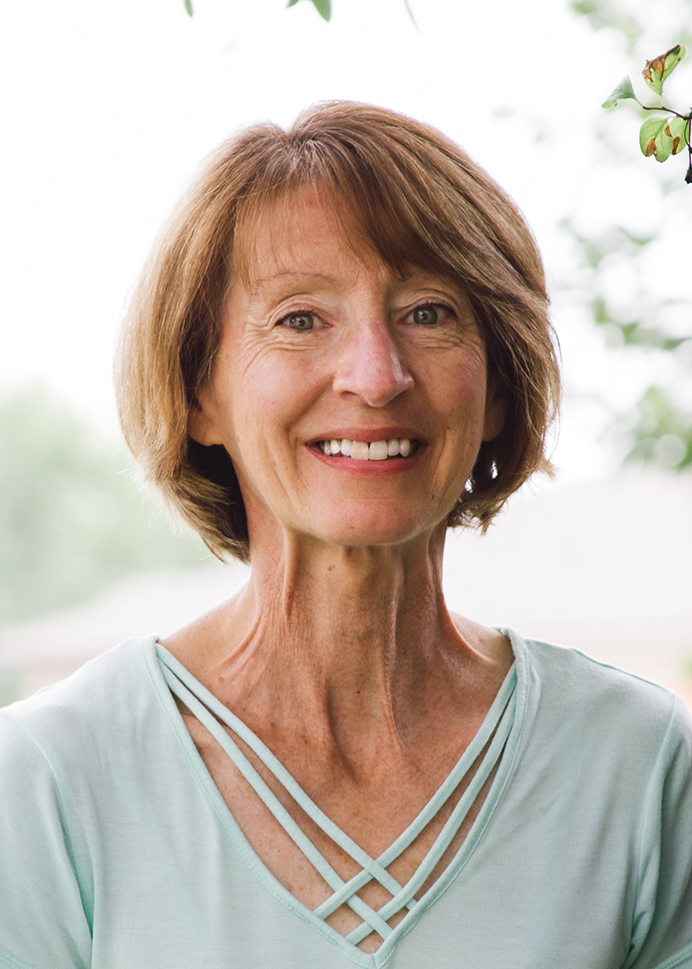 a woman in a light blue shirt smiles for the camera