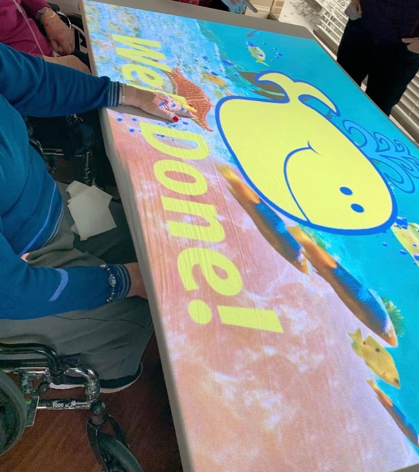 An image of a whale that says "Well Done!" is projected onto a table