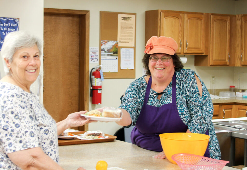 A woman hands a tuna sandwich kit to a Messiah Lifeways resident