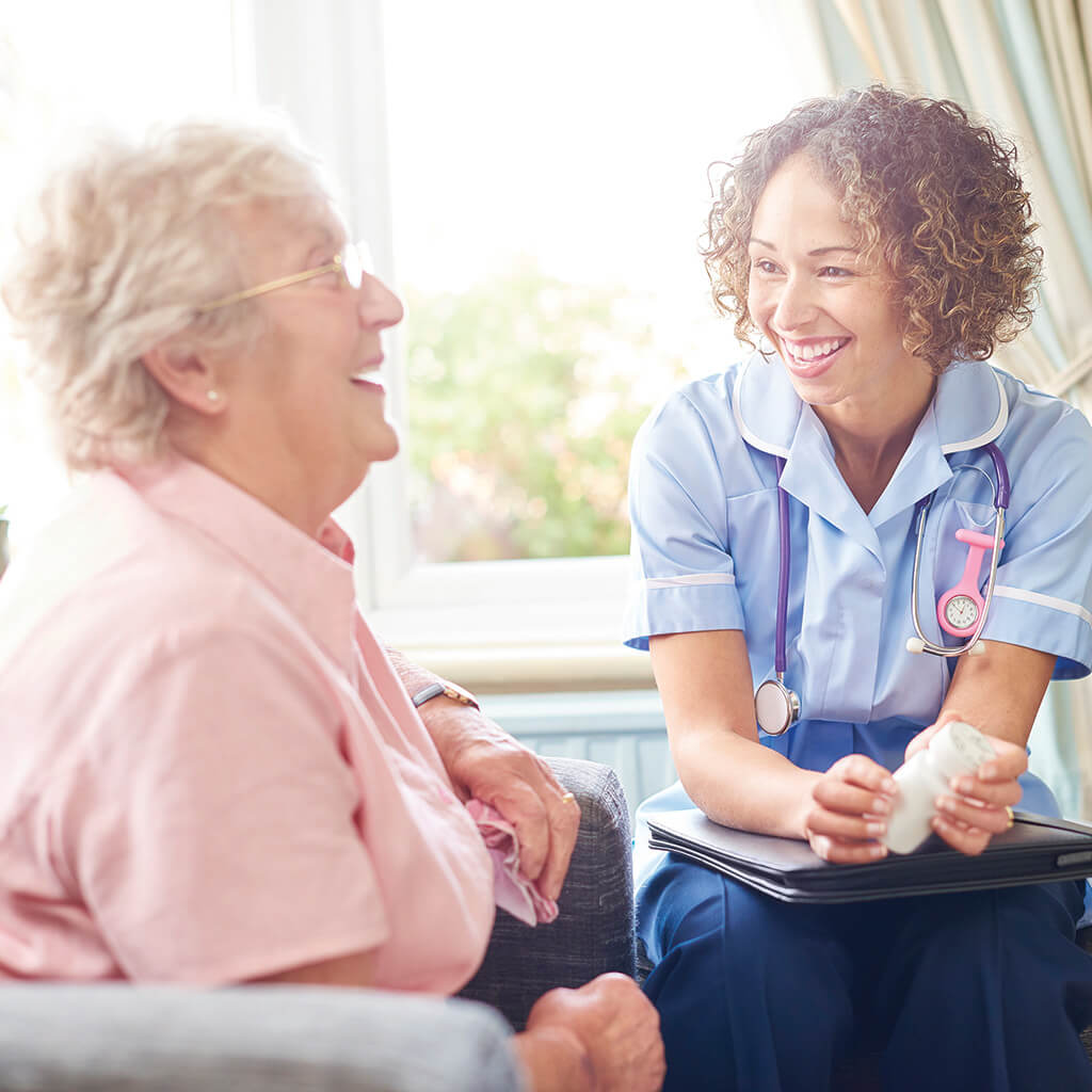 a nurse is smiling while talking to an elderly woman