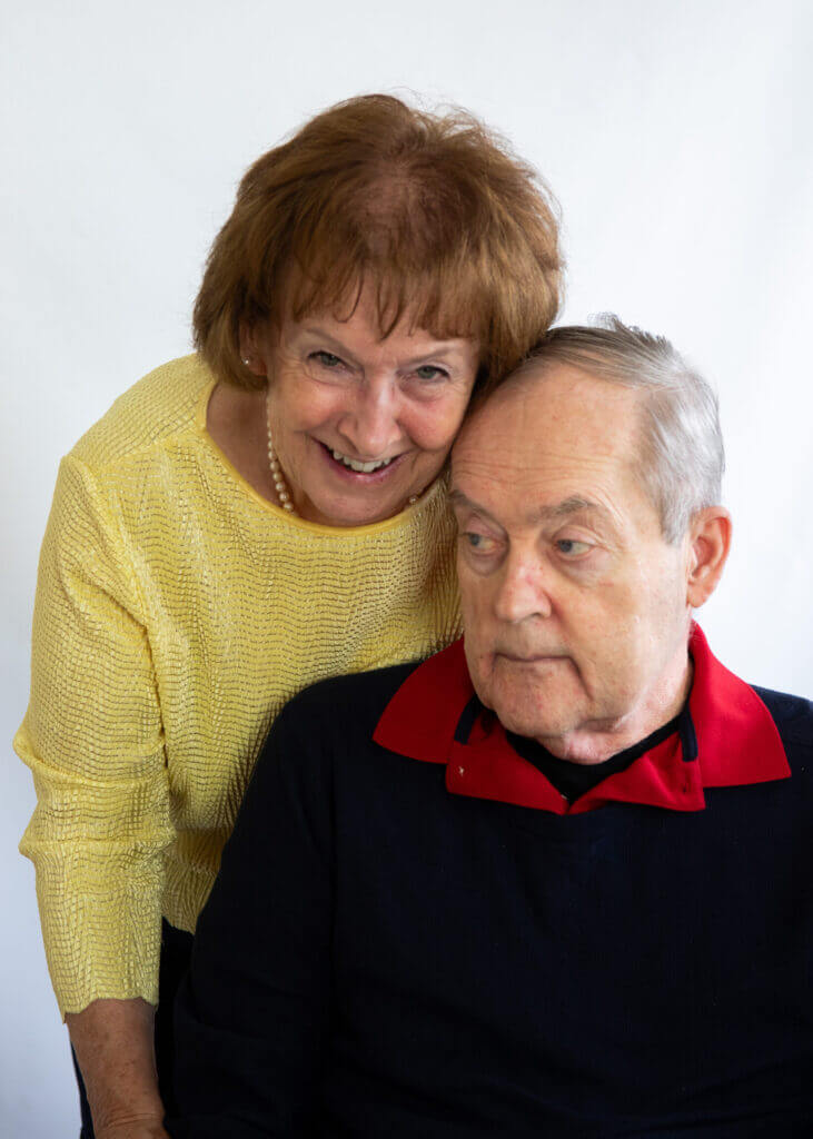 a woman in a yellow sweater stands next to an older man in a black sweater